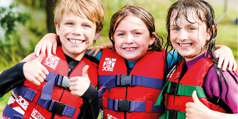 Three children thumbs up wearing lifejackets
